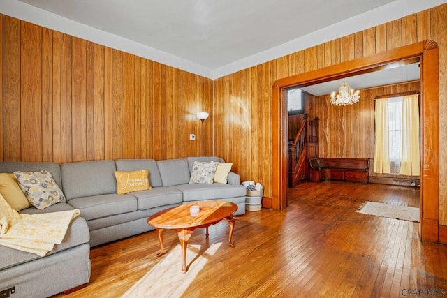 living room with hardwood / wood-style flooring, a chandelier, and wood walls