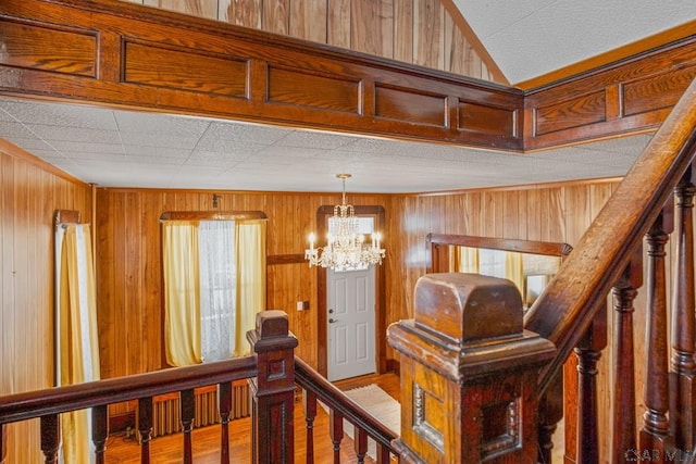 hall featuring hardwood / wood-style flooring, a notable chandelier, and wooden walls