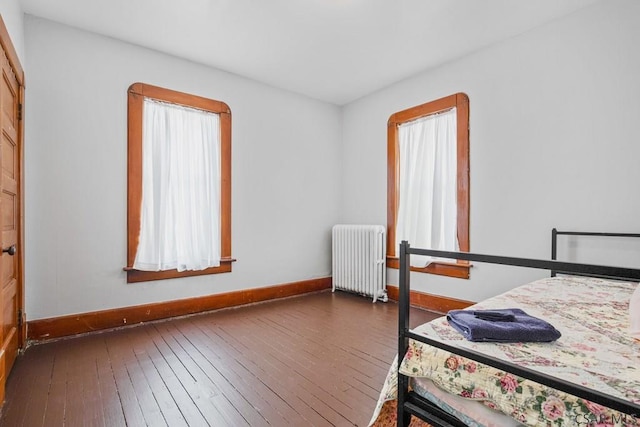 bedroom featuring multiple windows, radiator, and dark hardwood / wood-style flooring