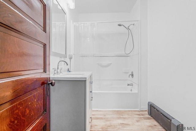 bathroom featuring baseboard heating, vanity, shower / bathtub combination with curtain, and hardwood / wood-style floors