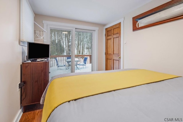 bedroom featuring access to exterior, baseboards, and wood finished floors