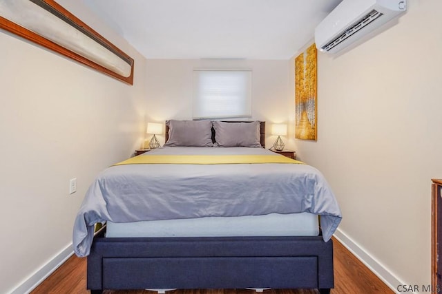 bedroom featuring dark wood-style flooring, a wall mounted AC, and baseboards