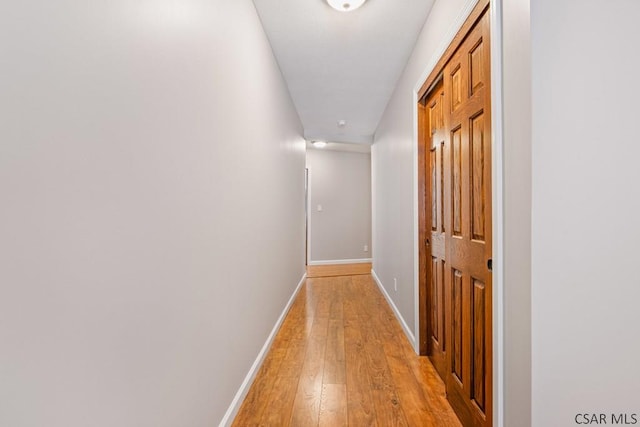 corridor featuring light wood finished floors and baseboards