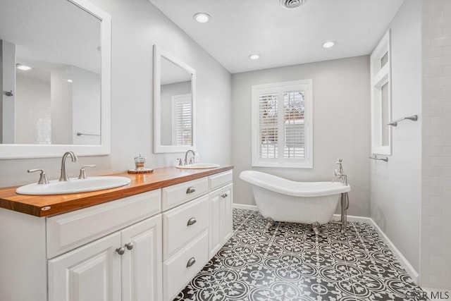 full bathroom with a soaking tub, a healthy amount of sunlight, and a sink