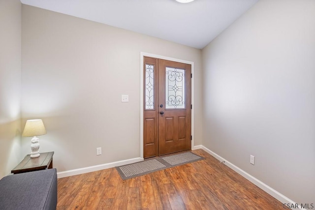 entryway featuring vaulted ceiling, wood finished floors, and baseboards