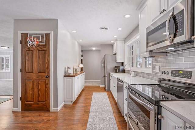 kitchen with white cabinetry, visible vents, backsplash, and stainless steel appliances