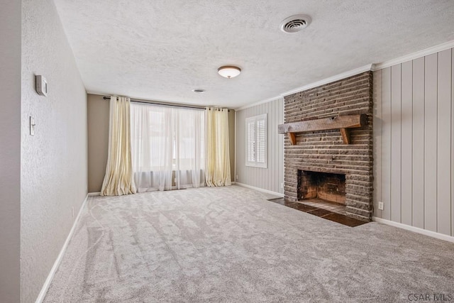 unfurnished living room featuring visible vents, carpet flooring, a brick fireplace, and a textured wall