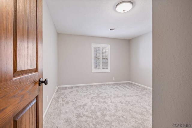 spare room with a textured wall, visible vents, baseboards, and carpet floors