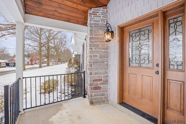 snow covered property entrance with a porch