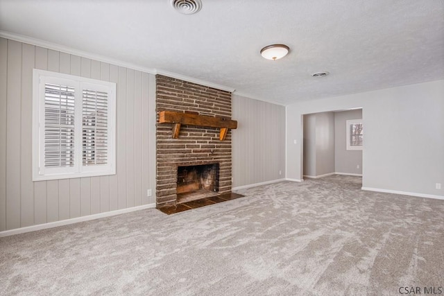 unfurnished living room featuring visible vents, ornamental molding, carpet flooring, baseboards, and a brick fireplace