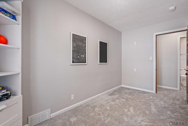 unfurnished bedroom with carpet flooring, baseboards, and visible vents