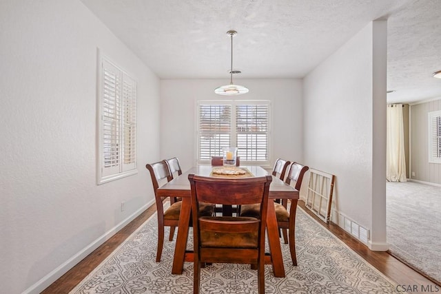 dining room with baseboards, a textured ceiling, and wood finished floors