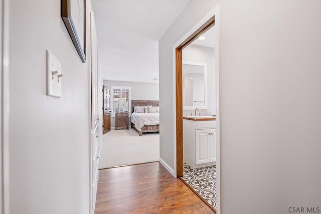 hallway featuring a sink and wood finished floors