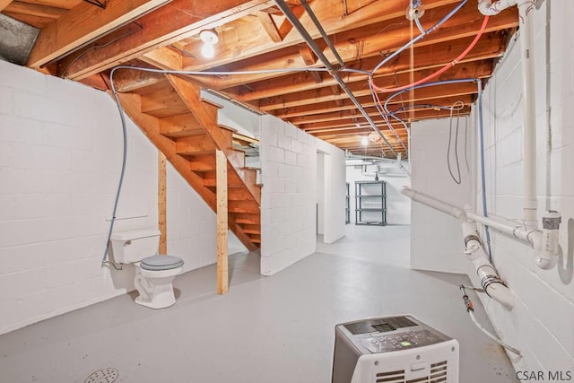 unfinished basement featuring stairs and heating unit