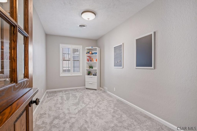 interior space with visible vents, a textured ceiling, baseboards, and a textured wall