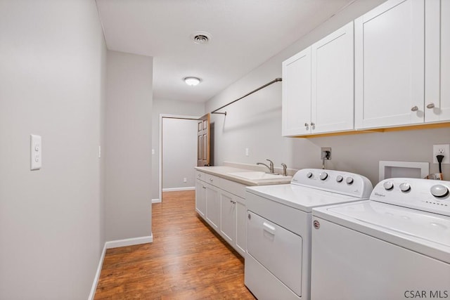 washroom featuring baseboards, light wood-style flooring, cabinet space, a sink, and washer and clothes dryer