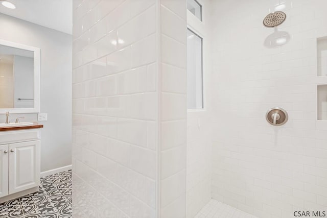 full bath with vanity, tile patterned flooring, and a tile shower