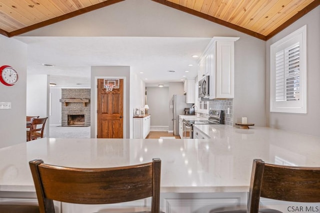 kitchen featuring wood ceiling, appliances with stainless steel finishes, a fireplace, and vaulted ceiling