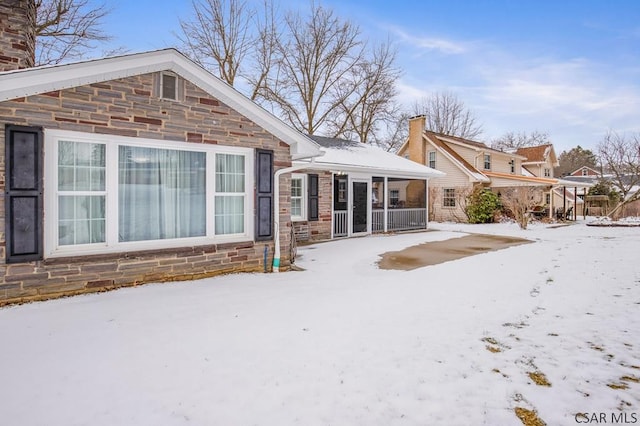 snow covered back of property featuring a chimney