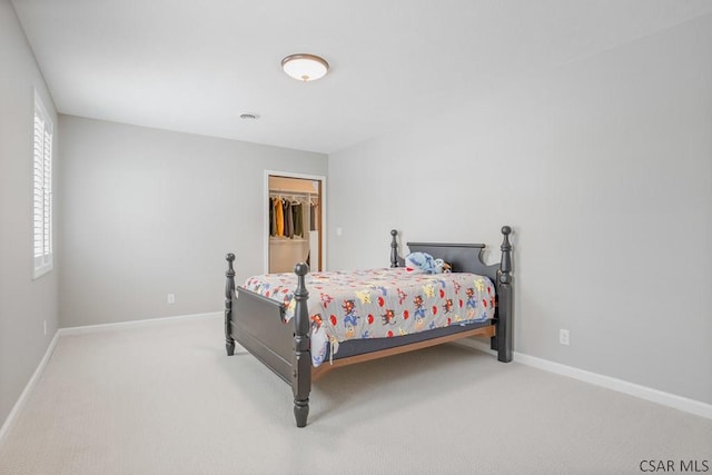 carpeted bedroom with baseboards and a spacious closet