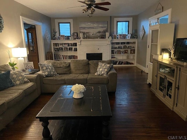 living room featuring a brick fireplace, dark hardwood / wood-style floors, and ceiling fan