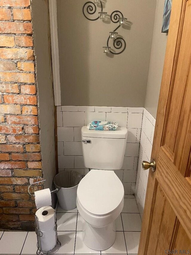 bathroom featuring tile patterned floors, toilet, and tile walls