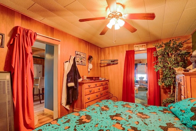 bedroom featuring wooden walls, wood finished floors, and ceiling fan