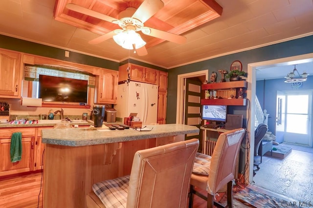 kitchen featuring a center island, a breakfast bar, light countertops, ornamental molding, and freestanding refrigerator