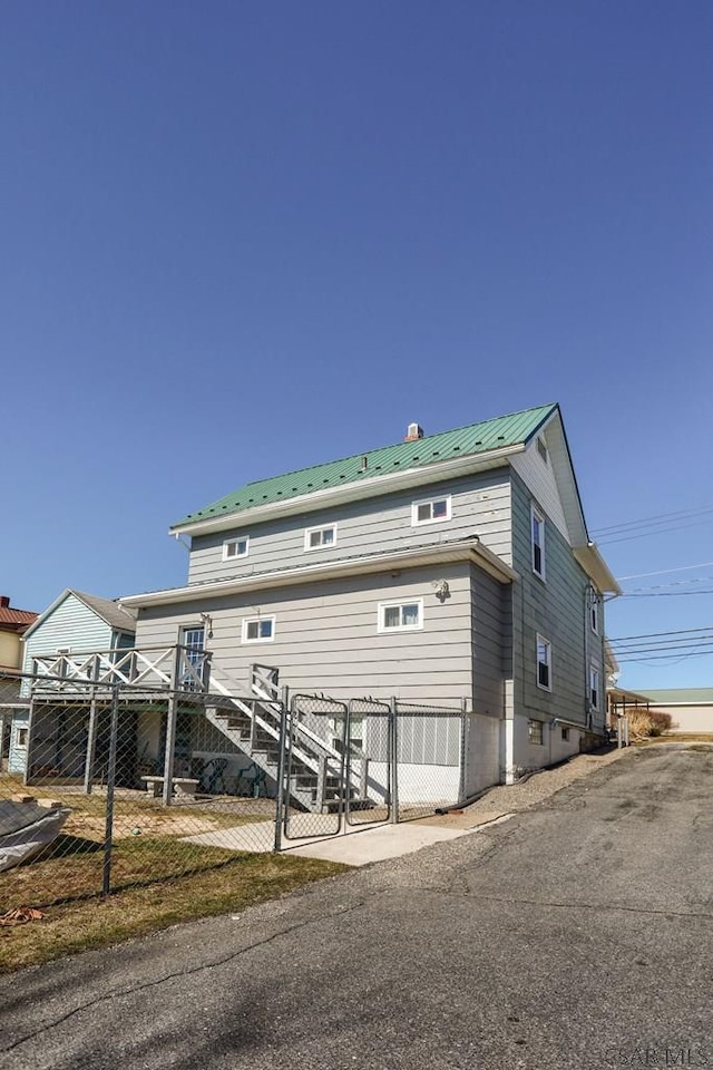 exterior space with a gate, metal roof, and fence