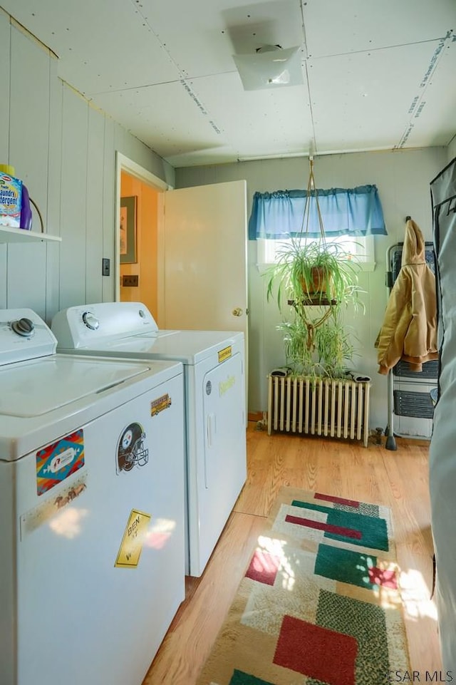 laundry area featuring laundry area, radiator, independent washer and dryer, and light wood-type flooring