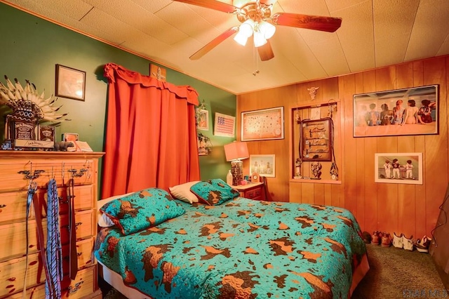 bedroom featuring ceiling fan, carpet floors, and wood walls