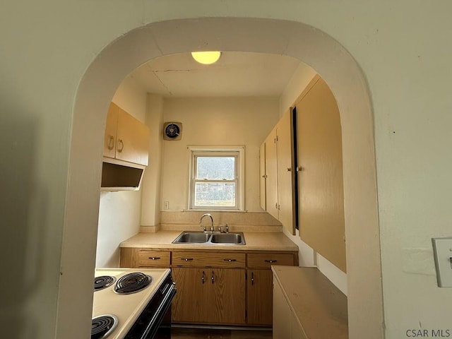 kitchen featuring arched walkways, electric stove, light countertops, and a sink