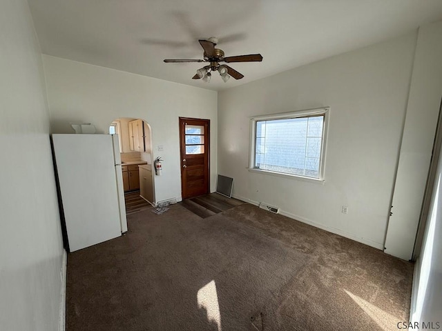 interior space with dark colored carpet, visible vents, and ceiling fan