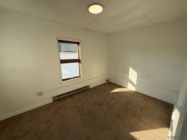 empty room with baseboard heating, dark carpet, visible vents, and baseboards