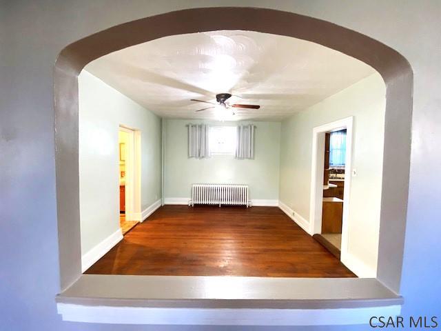 106 Lucetta St, Johnstown, PA 15905 - unfurnished room with radiator, arched walkways, a ceiling fan, and wood finished floors