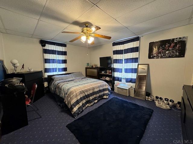 carpeted bedroom with ceiling fan and a paneled ceiling