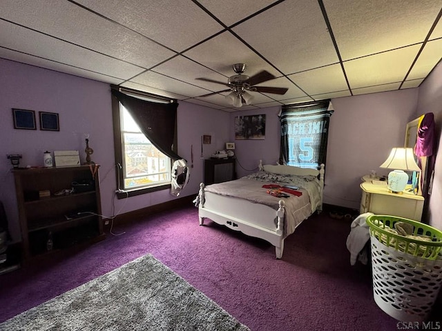 bedroom featuring dark colored carpet, a drop ceiling, and ceiling fan