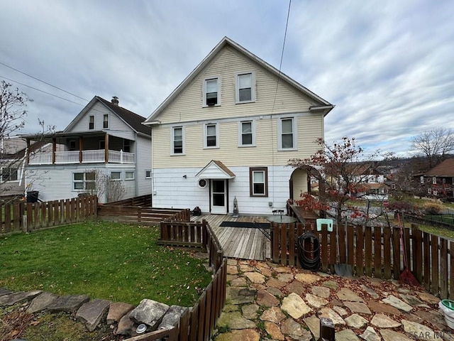 rear view of house with a wooden deck and a lawn