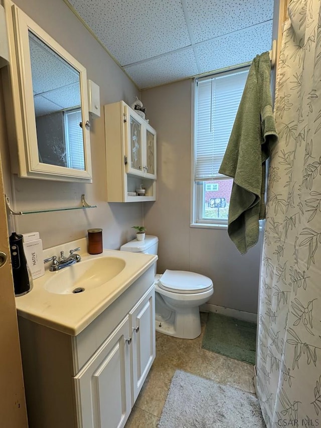 bathroom featuring vanity, a drop ceiling, and toilet