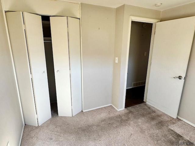 unfurnished bedroom with light carpet and a closet