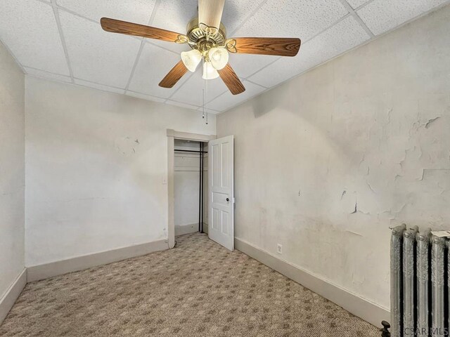 unfurnished bedroom with radiator, a drop ceiling, ceiling fan, and carpet flooring