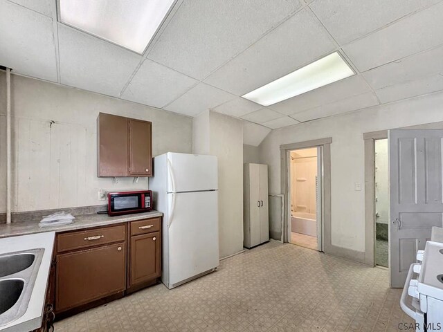 kitchen featuring sink, a drop ceiling, and white appliances