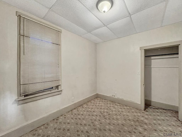 unfurnished bedroom featuring carpet floors, a closet, and a drop ceiling