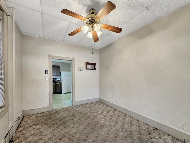 carpeted spare room featuring ceiling fan and a drop ceiling