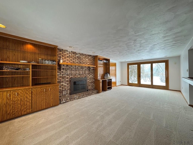 unfurnished living room with light colored carpet, a brick fireplace, and a textured ceiling