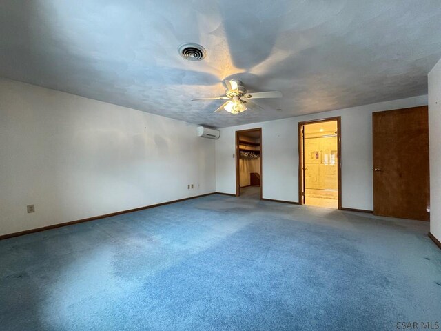 unfurnished bedroom with ensuite bath, ceiling fan, carpet floors, a walk in closet, and a closet