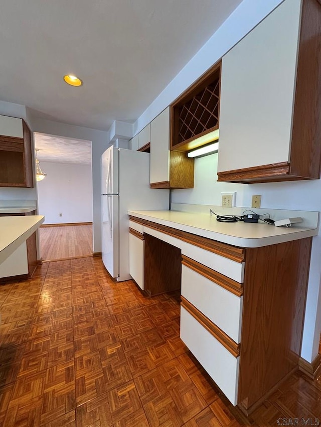 kitchen with white cabinetry, white fridge, and dark parquet flooring