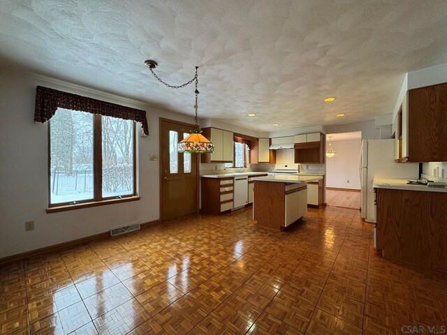 kitchen with decorative light fixtures, dishwashing machine, dark parquet flooring, a center island, and a textured ceiling