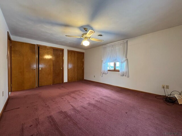 unfurnished bedroom featuring multiple closets, ceiling fan, and carpet flooring