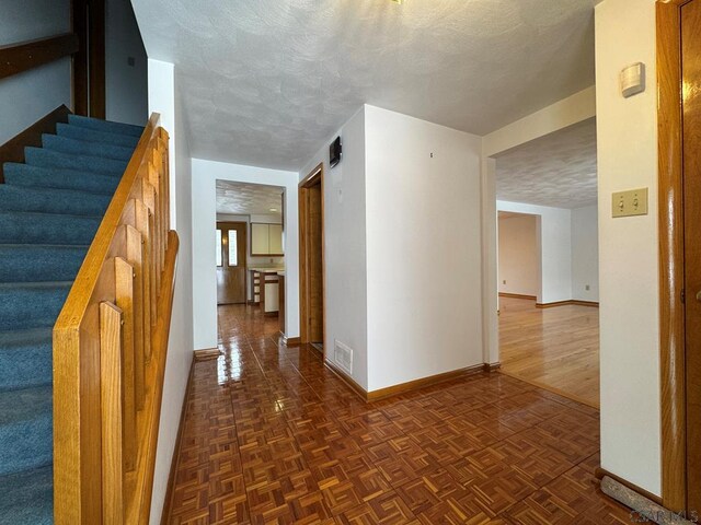 hallway featuring a textured ceiling and dark parquet floors